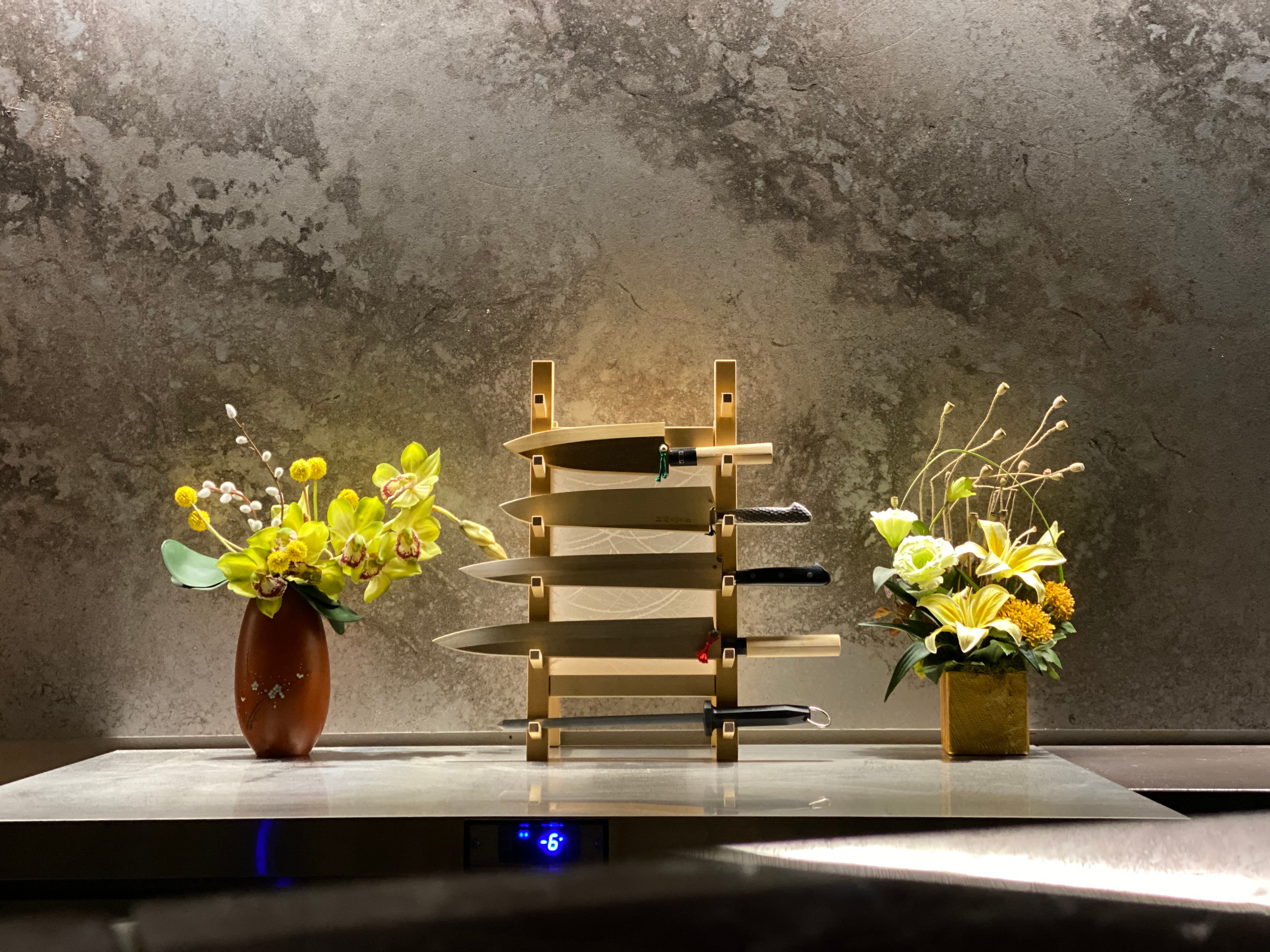 Japanese knife display with seasonal flower arrangements at Kanpai Omakase Room